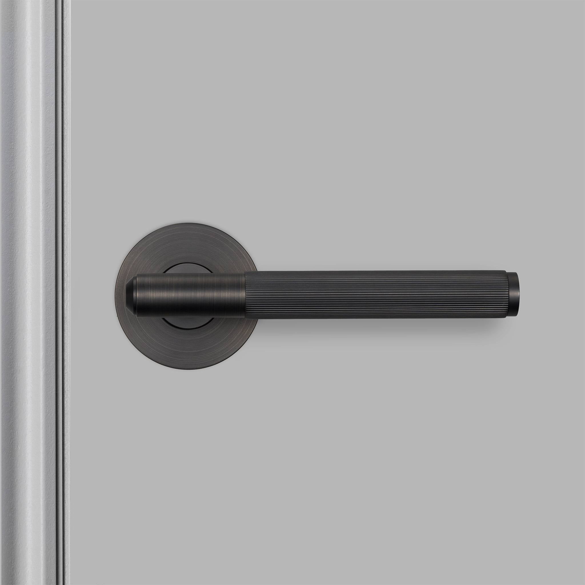 Buster + Punch Linear deurkruk op rozet in smoked bronze, gemonteerd op deur